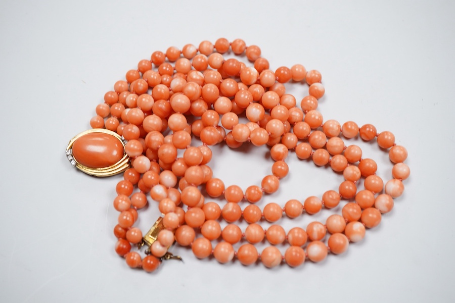 A coral necklace, composed of three strands of coral beads measuring approximately 5.1-6.6mm diameter, to a gold clasp set with a coral cabochon and brilliant-cut diamonds, mounted in gold, length 45.5cm, stamped 14K, ca